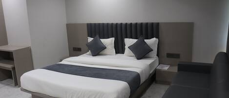 Una habitación de hotel moderna con una cama grande, una mesita de noche y un banco empotrado.