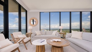 A spacious balcony with a view of the city and sea, furnished with a sofa, chairs, and round tables. - Phoenix Gulf Shores Ii 2501 4 Bedroom Condo (Gulf Shores)