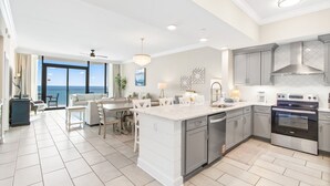 A modern kitchen with grey cabinets, a large island, and a view to the outside. - Phoenix Gulf Shores Ii 1502 3 Bedroom Condo (Gulf Shores)