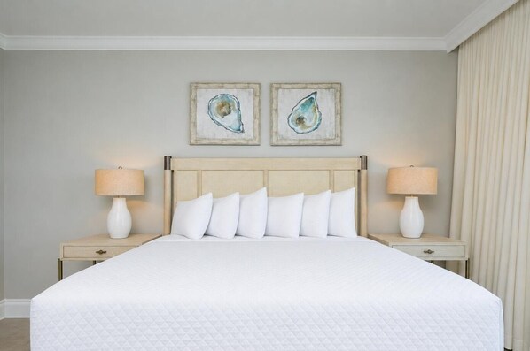 Una habitación de hotel con una cama grande, dos mesitas de noche con lámparas y dos cuadros colgados en la pared.
