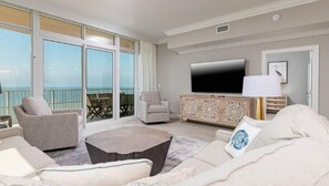 Relax in this stylish living area with a large flat-screen TV, comfortable sofa, and balcony with outdoor views.