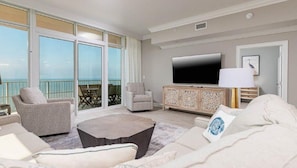Relax in this stylish living area with a large flat-screen TV, comfortable sofa, and balcony with outdoor views.