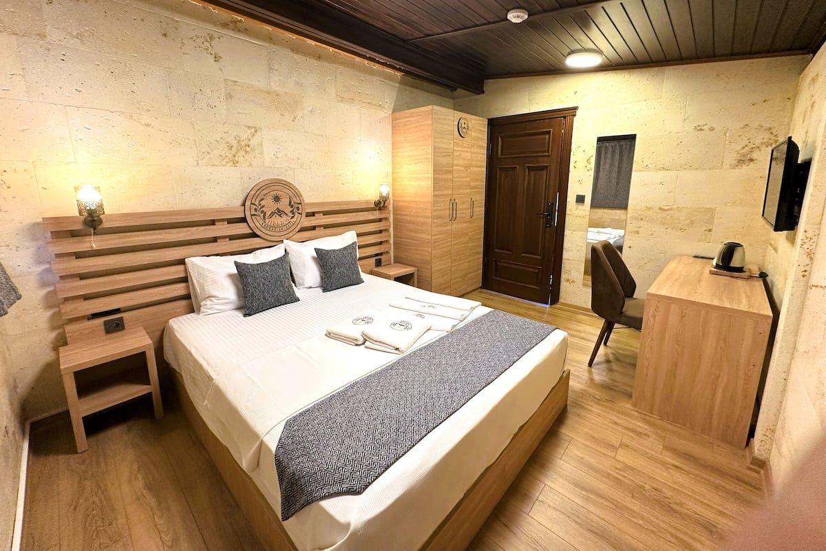 A bedroom with a wooden bed, bedside tables, a wardrobe, a desk, and a mirror.