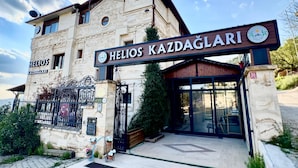Um edifício com uma placa que diz 'Helios Kazdaglari' e uma entrada por um portão.