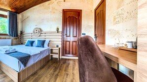 Um quarto aconchegante com uma cama, uma cadeira, uma mesinha e uma escrivaninha de madeira.