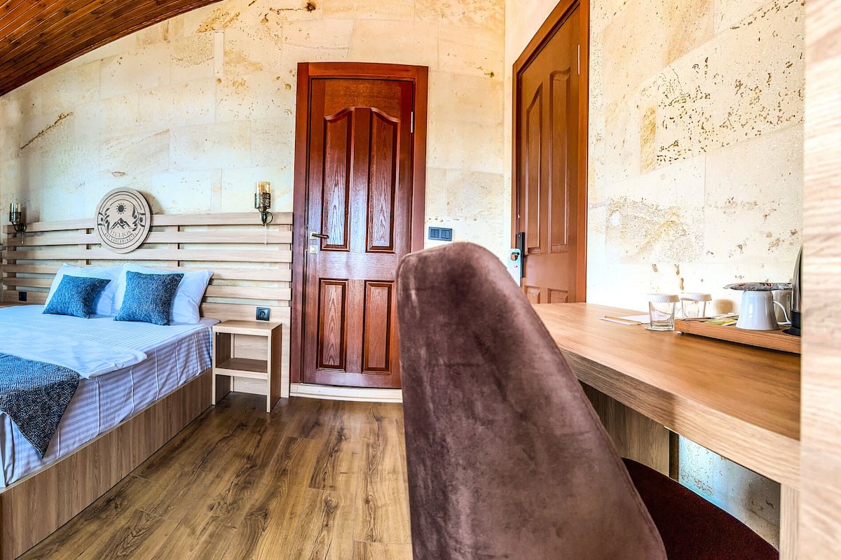 A cozy room with a bed, a chair, a small table, and a wooden desk.