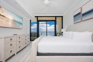A bedroom with a large bed, a dresser, a ceiling fan, and a view of the sky through a balcony door. - Phoenix Gulf Shores Ii 1205 4 Bedroom Condo (Gulf Shores)