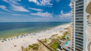A beach view from a high-rise hotel with a pool and beach umbrellas.