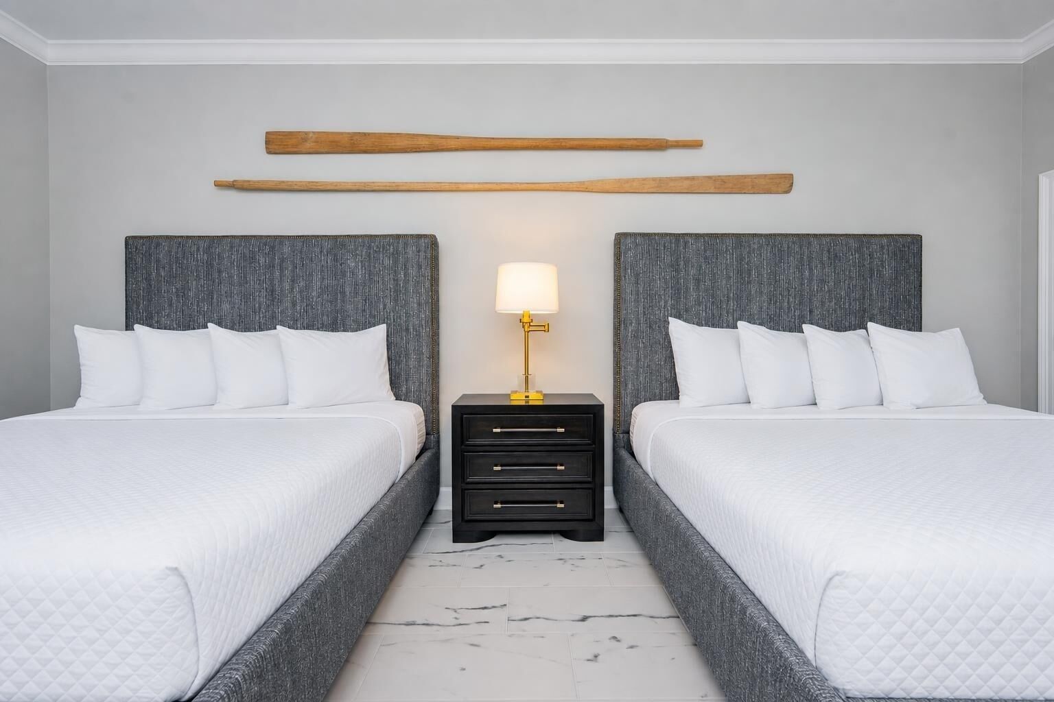 A double bed room with a grey headboard, a bedside table with a lamp, and a wooden shelf above the bed.