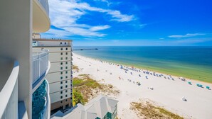 A high-rise hotel overlooking a beach with a pier in the distance.