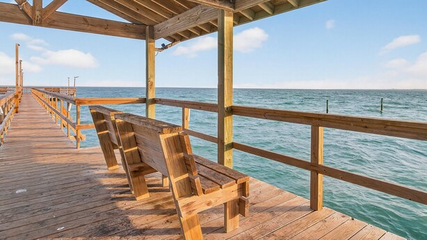 Une jetée en bois qui s’avance dans la mer, avec des bancs disposés le long de la promenade.