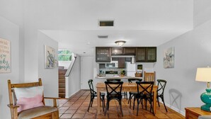 Une cuisine spacieuse avec un coin repas, comprenant une table à manger en bois, des chaises et un escalier menant à l’étage supérieur.