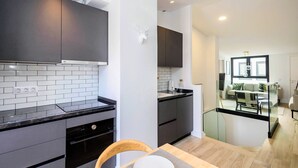 Una cocina moderna con armarios oscuros, un salpicadero de azulejos blancos y un comedor con separador de vidrio.