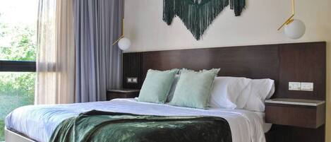 Une chambre à coucher moderne avec un grand lit, une tête de lit sombre et un plaid vert.