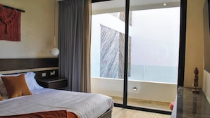 A modern hotel room with a large bed, a nightstand, a lamp, and a view of the sky through a large window. - NEW LISTING** This premium two-bedroom condo offers the best of both worlds - set in one of Tulum’s most desirable areas, you’re just minutes from shops, restaurants, and the main road to the beach. (Tulum)