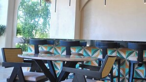 A restaurant with a thatched roof, geometric patterned walls, and modern furniture. - NEW LISTING** This premium two-bedroom condo offers the best of both worlds - set in one of Tulum’s most desirable areas, you’re just minutes from shops, restaurants, and the main road to the beach. (Tulum)