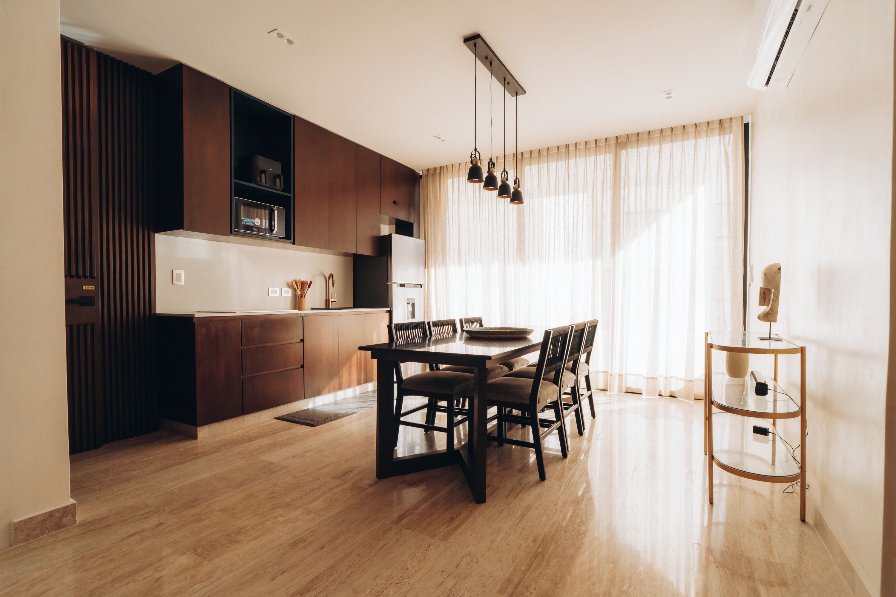 A modern kitchen with dark wood cabinets, a built-in microwave, and a stainless steel refrigerator.