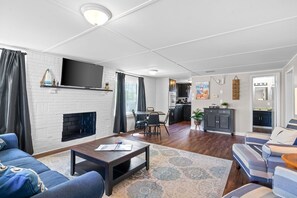 A modern living room with a fireplace, a television, and a dining area.