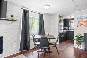 A modern kitchen with dark cabinets, a built-in oven, and a window with curtains.