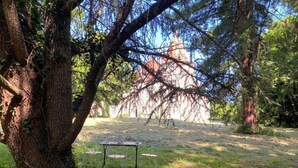 Una mesa de picnic con sillas en un área boscosa, con vista a un edificio a lo lejos.