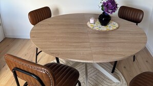 Ein runder Holztisch mit einem Blumenstrauß, umgeben von vier braunen Ledersesseln.