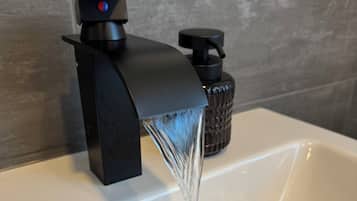 Ein modernes Waschbecken mit einem schwarzen Wasserhahn und einer Seifenspender.