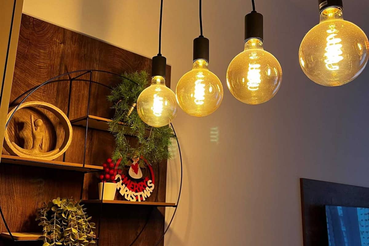 Een modern interieur met een houten plank waarop een kerstversiering, een klein plantje en een decoratieve kom staan.