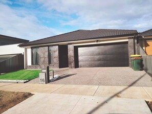 Una casa moderna de dos pisos con garaje, césped cuidado y entrada para vehículos.
