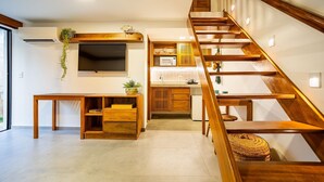 A modern kitchen with wooden cabinetry, a built-in microwave, and a wooden staircase leading to an upper level. - ARARA HOUSE JERI (Jijoca de Jericoacoara)