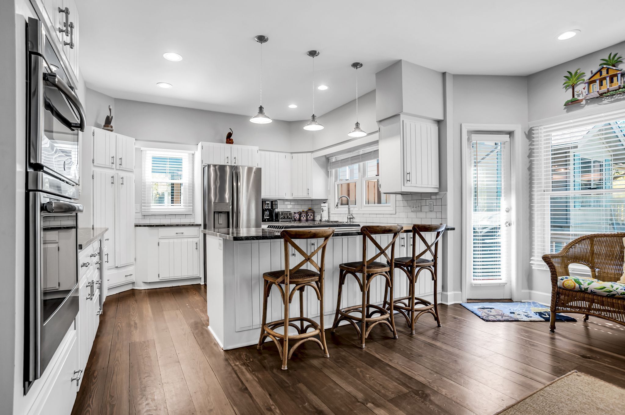 A modern kitchen with white cabinetry, stainless steel appliances, and a central island with bar stools.