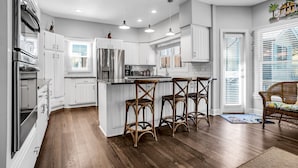 A modern kitchen with white cabinetry, stainless steel appliances, and a central island with bar stools.