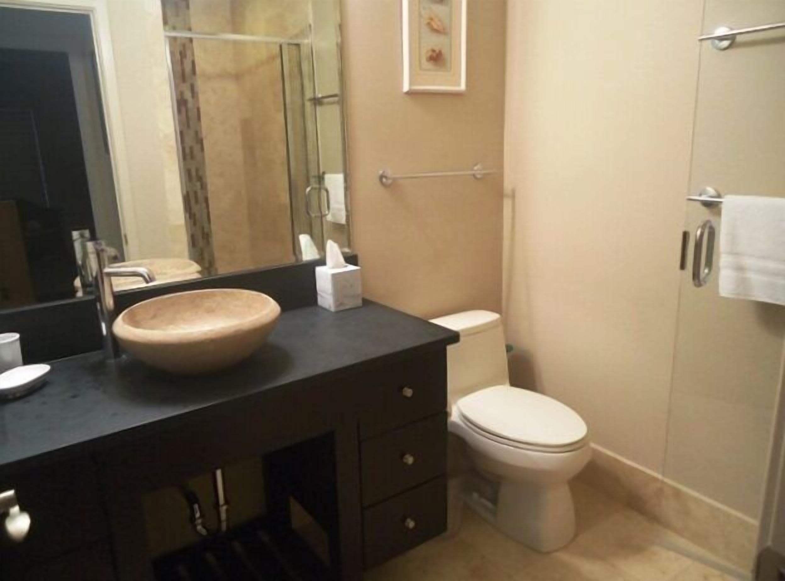 A bathroom with a wooden sink, a toilet, a towel rack, and a mirror.