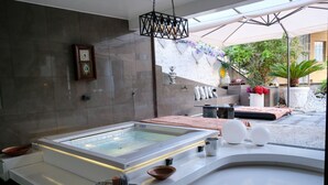 A modern spa area with a large hot tub, a wall-mounted clock, and a decorative light fixture. - Vip garden and jacuzzi seaview in the hearth of downtown (La Spezia)