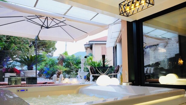 An outdoor seating area with umbrellas, a fountain, and potted plants. - Vip garden and jacuzzi seaview in the hearth of downtown (La Spezia)