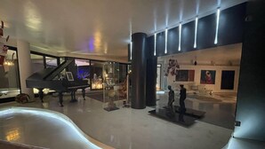 A spacious lobby with a grand piano, modern art sculptures, and a sleek, curved ceiling design. - Vip garden and jacuzzi seaview in the hearth of downtown (La Spezia)