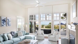 Un salon spacieux doté d’une grande fenêtre, d’un ventilateur de plafond et d’une cheminée.