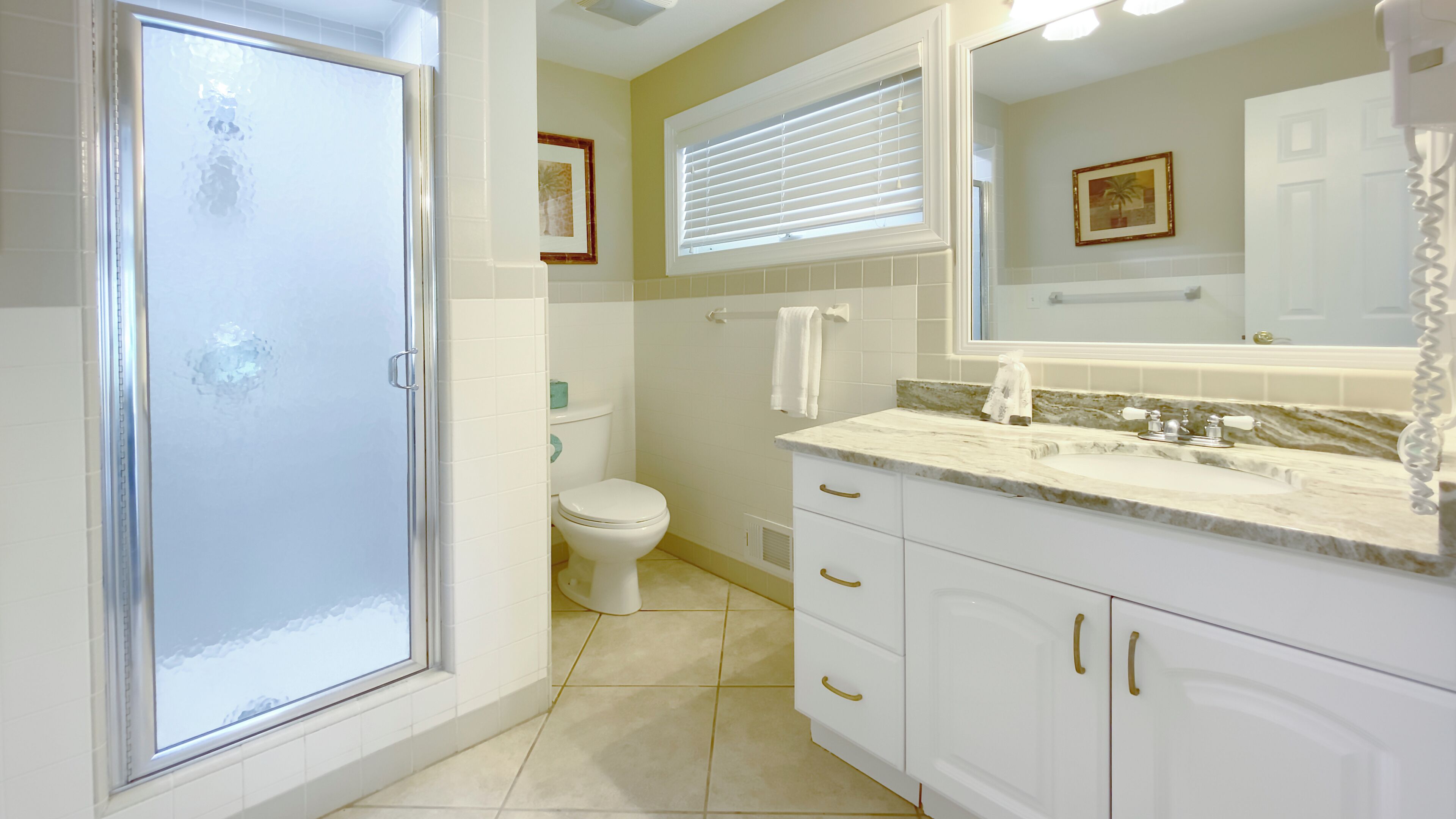 Une salle de bain équipée d’une douche, de toilettes, d’un lavabo et d’un grand miroir.