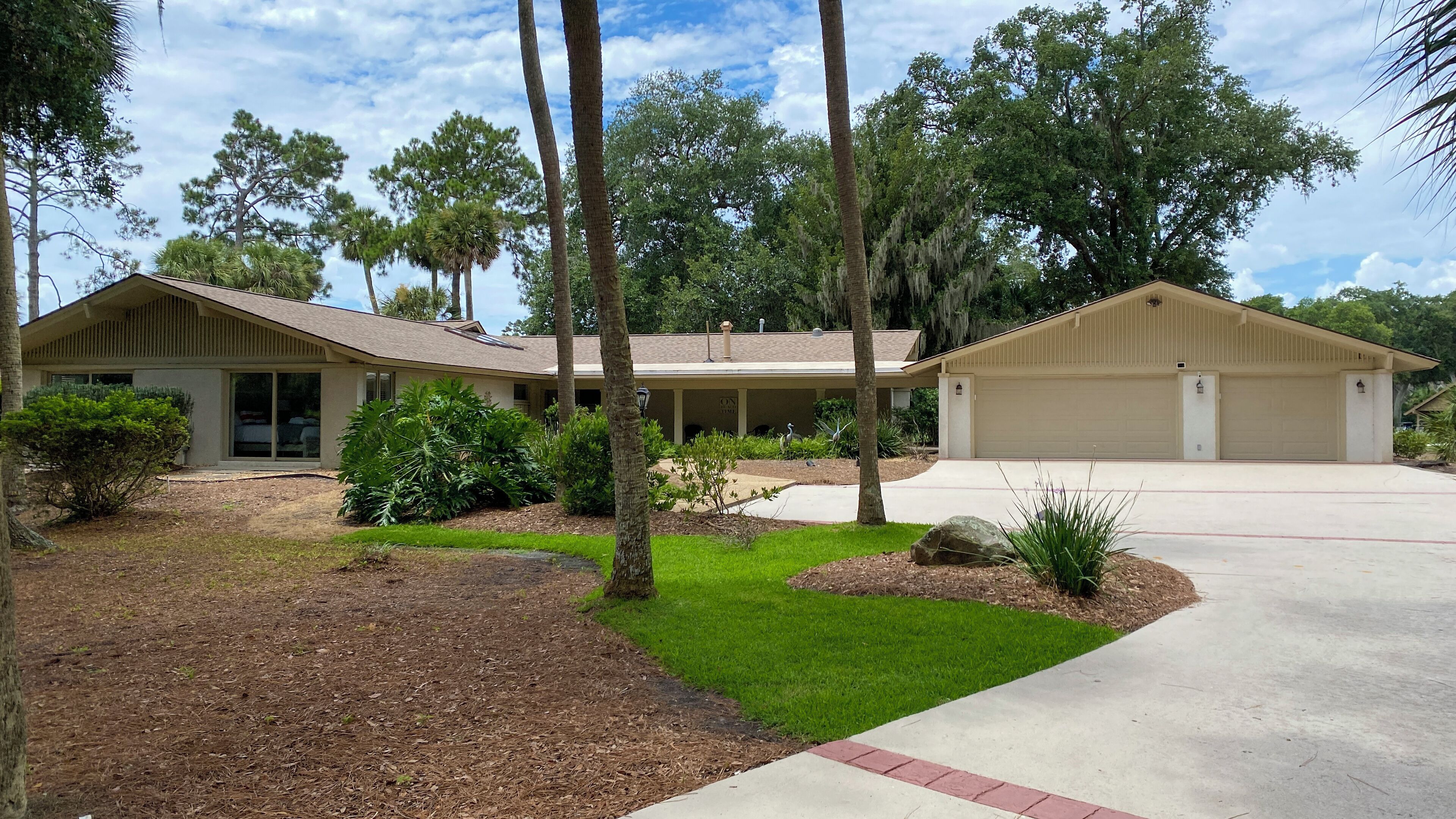 A two-story house with a covered porch, a garage, and a landscaped front yard with trees and shrubs.