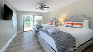 A bedroom with two beds, a ceiling fan, a TV, and a view of the outdoors. - 34 North Live Oak at The Sea Pines Resort (Hilton Head Island)