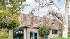 Une maison en pierre avec un toit en tuiles, une porte en verre et un petit jardin.