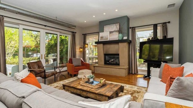 A modern living room with a fireplace, large windows, and a television. - Juniper Presents: The Vineyard Loft - Cool Harbert Loft Near Beach with Fire Pit (Harbert)