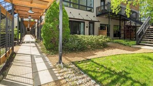 A modern building with a covered walkway, outdoor seating area, and a staircase leading to an upper level. - Juniper Presents: The Vineyard Loft - Cool Harbert Loft Near Beach with Fire Pit (Harbert)