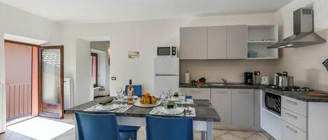 A modern kitchen with a dining area, featuring a central island, blue chairs, and a variety of appliances.
