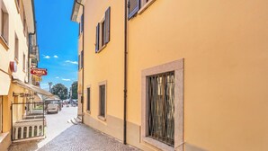 A narrow cobblestone street with buildings on either side, a sign for a restaurant, and a parked van. - Nel Cuore Di Baveno 50m from Lake (Baveno)
