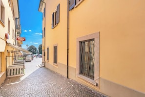 Une ruelle étroite pavée, bordée de bâtiments des deux côtés, avec une enseigne indiquant un restaurant et un fourgon stationné.