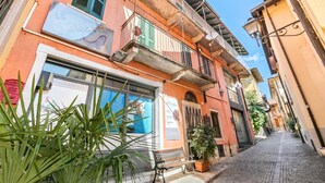 A narrow street with a building featuring a balcony, a bench, and a potted plant. - Nel Cuore Di Baveno 50m from Lake (Baveno)