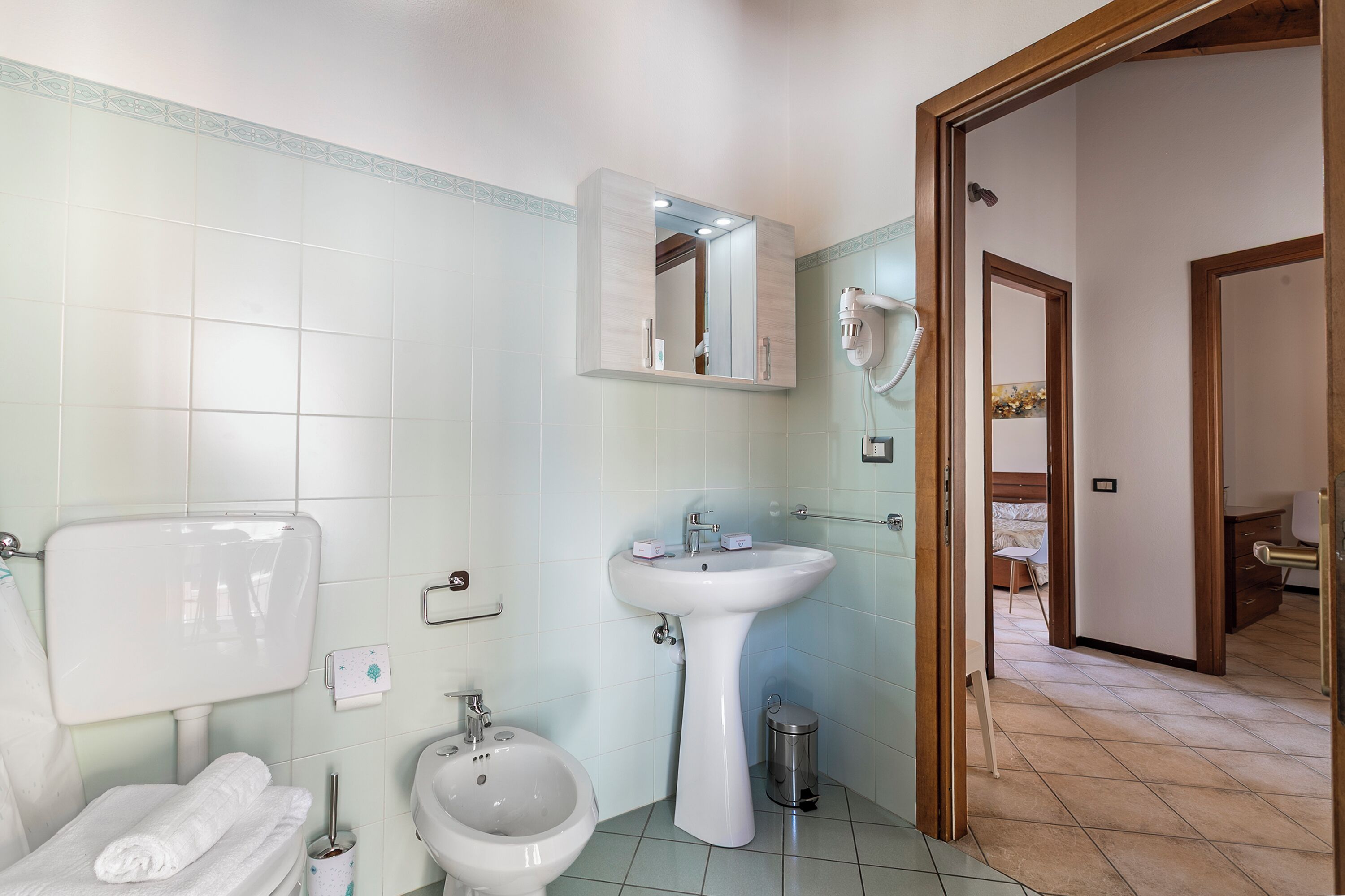 Un baño con inodoro, bidé, lavabo y espejo.
