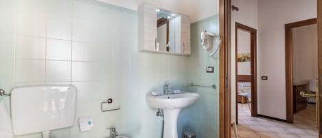 Un baño con inodoro, bidé, lavabo y espejo.