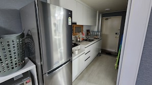 A compact kitchen with a stainless steel refrigerator, white cabinets, and a small countertop.