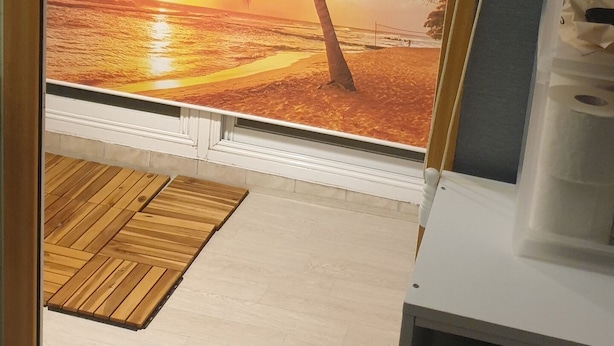 A room with a beach scene mural, a wooden door mat, and a hanging light fixture.